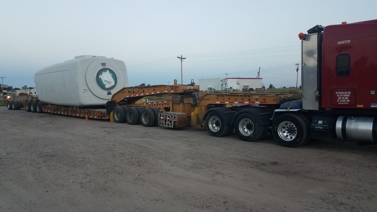 Wind turbine nacelle on a lowboy trailer at dusk